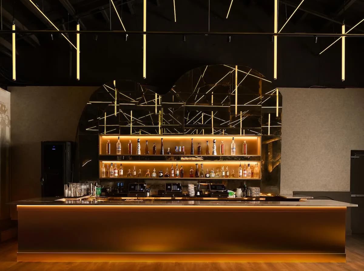 Mr. Ivy bar with gold amber lighting and arch mirror backdrop — commercial build by Treacy Brothers